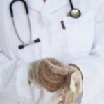 pexels-photo-3825586-3825586 Faceless ethnic medical worker in lab coat and stethoscope taking of transparent gloves after approaching patients for examination in modern hospital