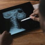 pexels-photo-5452223-5452223 Doctor examining a spinal x-ray on a tablet using a stylus. Modern medical analysis.